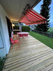 南达2,5 pièces à Haute-Nendaz, grande terrasse, piscine, sauna, tennis的木制甲板上配有红色的桌椅