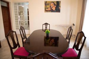 纳纽基Cottage in Nanyuki, Maiyan; Swara Ranch #28的餐桌、粉红色软垫椅子、桌子和绘画