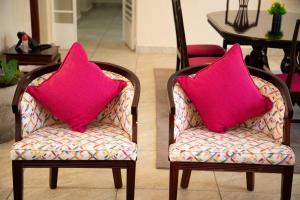 纳纽基Cottage in Nanyuki, Maiyan; Swara Ranch #28的客厅配有两把带粉红色枕头的椅子