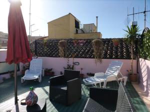 卡利亚里Rosa's Apartment with Terrace的屋顶上带椅子和遮阳伞的天井