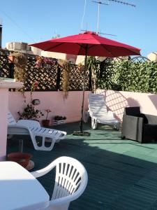 卡利亚里Rosa's Apartment with Terrace的庭院配有白色椅子和红色遮阳伞