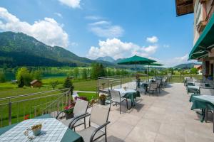 魏森湖Wiesenhof, Hotel direkt am See的庭院配有桌椅,背景为山脉