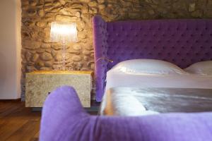 ArlateIl Portico - 1711 Luxury Guest House的一间卧室配有紫色的床和一张带台灯的桌子