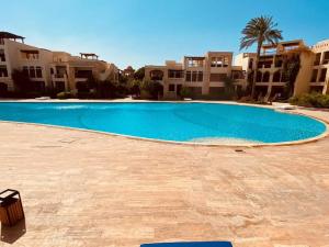 亚喀巴Sea View Apartment at Tala Bay Resort in Aqaba的一座大型蓝色游泳池,位于部分建筑前