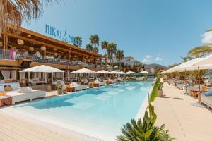 蒂瓦特Nikki Beach Resort & Spa Montenegro的度假村的游泳池配有椅子和遮阳伞