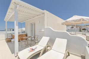 纳克索乔拉Elite Suites Naxos的阳台配有白色椅子和遮阳伞。