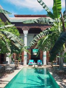 马拉喀什希利缇内Spa庭院旅馆的一座带椅子和树木的建筑的庭院内的游泳池