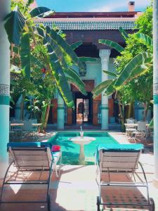 马拉喀什希利缇内Spa庭院旅馆的一个带两把椅子的游泳池和一个喷泉