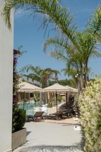 LalëzElite Bay Hotel Lalez Durres的一个带桌子和遮阳伞以及棕榈树的度假村