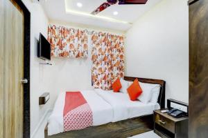 拉杰果德Hotel Blue Leaf的一间卧室配有带橙色枕头的床和电视。