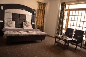 斯利那加Hotel Al Azrah的卧室配有一张床和一张桌子及椅子