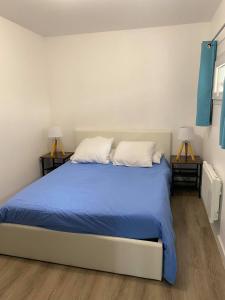 Saint-Mitre-les-RempartsL'Olivier的一间卧室配有一张带蓝色床单的床和两盏灯。