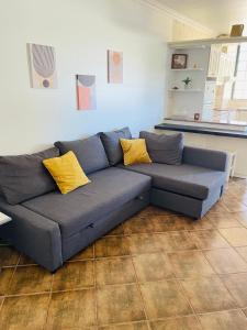 阿尔沃尔Apartamento Praia do Vau的客厅配有蓝色沙发及黄色枕头