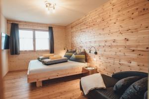 霍赫林德Hiasl Zirbenhütte的一间卧室设有木墙、一张床和一张沙发