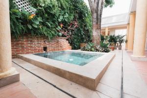 卡塔赫纳Casa Jaguar Hotel Boutique的一座位于庭院内的游泳池,庭院内有砖墙