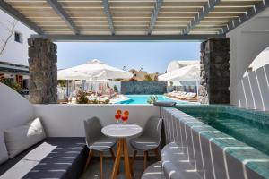 卡马利圣托里尼阿马拉套房旅馆的游泳池旁带桌椅的天井