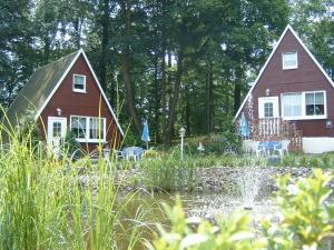 塔勒Ferienpark Rosstrappe的树林里两个红色的小屋,有一个池塘