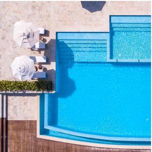 蓬塔卡纳Apartamento Acceso Directo a la piscina A-108, A-120, A-117 y B-137的享有带遮阳伞和椅子的游泳池的顶部景致