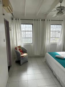基督教堂市Home2Home Guesthouse的一间卧室配有一张床、一把椅子和窗户。
