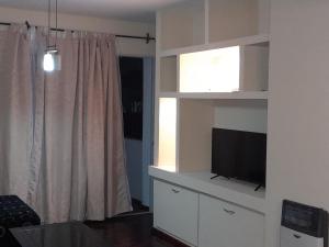 门多萨Departamento ciudad de Mendoza的客厅设有白色架子上的平面电视。