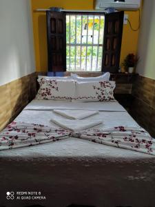 莫罗圣保罗Casa Goio Morro de São Paulo的一张铺有白色床单和红色鲜花的床
