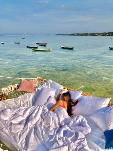 蓝梦岛Indigo Blue Ceningan的一位女士躺在海滩上枕头下面