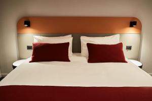 皮亚特拉-尼亚姆茨Atlas Aparthotel的一张大床,上面有两个红色的枕头