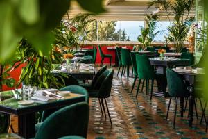 陶尔米纳卡尔洛塔别墅酒店的一间设有桌椅的餐厅,种植了植物