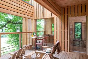 Maison-MaugisNuits Perchées的小木屋设有门廊,配有桌椅