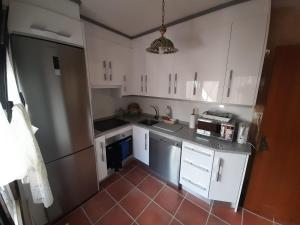 埃尔阿雷纳尔La casa del puerto的厨房配有白色橱柜和红色瓷砖地板。