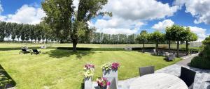 WervikHotel het Elsland的草地上种着桌椅和鲜花的公园