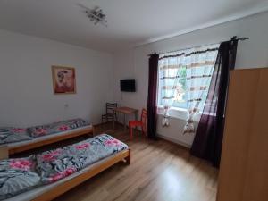 基约夫Rodinný Penzion Kyjov的客房设有两张床、一张桌子和一扇窗户。
