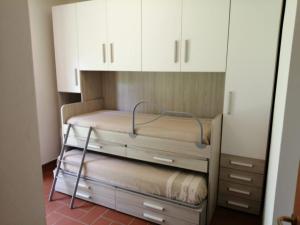格罗塞托港Residence LA CANOVA的配有白色橱柜的客房内的双层床
