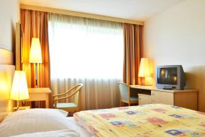 布拉格奥林匹克阿耳忒弥斯酒店的酒店客房,配有床和电视