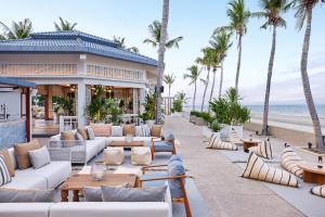 七岩Dusit Thani Hua Hin的一个带沙发和桌子以及棕榈树的度假庭院