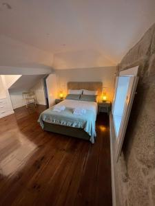 波尔图A Portuguesa Guest House的一间卧室设有一张大床,铺有木地板