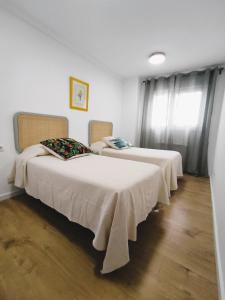 马里亚诺Apartamento Santander Maliaño的配有白色墙壁和木地板的客房内的两张床