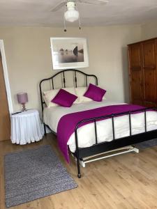 切尔滕纳姆The Bell Inn的一间卧室配有一张带紫色床单和枕头的床。