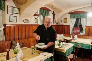 Sankt Peter in HolzLandhaus Gritschacher的一家餐厅里拿着盘子的老人
