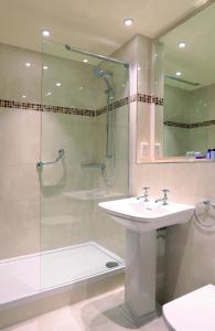 威根麦克唐纳凯利苑酒店& Spa的一间带水槽和玻璃门淋浴的浴室