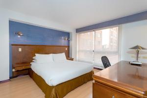 波哥大GIO Suites Parque 93 Bogotá的卧室配有白色的床、书桌和窗户。
