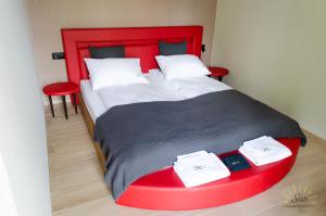 SominySun Apartamenty Sominy的一张带红色床头板的床和两张红色椅子