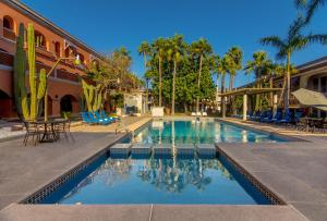 瓜伊马斯Gamma Guaymas Armida Hotel的一座带椅子和棕榈树的游泳池以及一座建筑