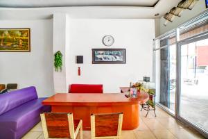 棉兰OYO 91224 Brayan Guest House的客厅配有桌子和紫色沙发