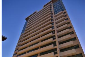 坎普斯戈伊塔卡济斯Flat Hotel América Campos Pelinca 301的一座高大的建筑,背后是蓝天