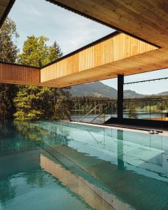 基茨比厄尔Alpenhotel Kitzbühel am Schwarzsee - 4 Sterne Superior的一座房子,设有一座带木屋顶的游泳池