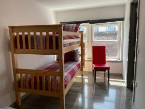因弗内斯Rooms in Inverness的一间卧室设有两张双层床和一张红色椅子