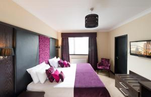 拉克霍尔The Popinjay Hotel的一间卧室配有一张大床,提供紫色和白色枕头