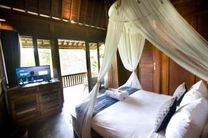德格拉朗Sebatu Tulen Villa的一间卧室配有一张天蓬床和一台电视机