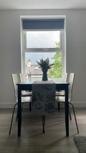 贝尔法斯特CityGo Apartments Queens Wellington的餐桌和椅子,上面有花瓶